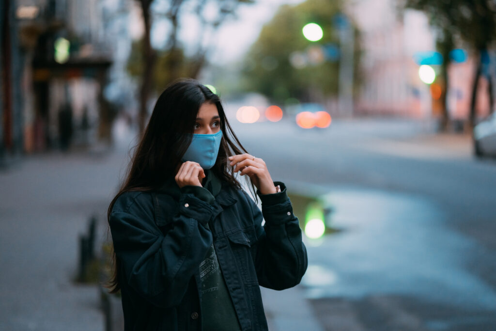 A woman standing on a city street at dusk, representing the hustle and bustle of ground-level urban living.